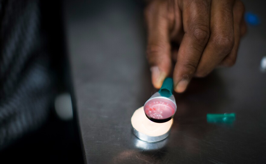 A drug user prepares a hit of heroin inside VANDU's supervised injection room.