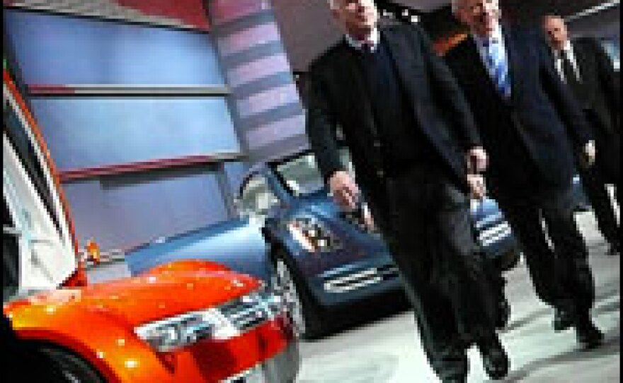 Sen. John McCain and Sen. Joe Lieberman walk across the Chrysler stage at the auto show Monday.