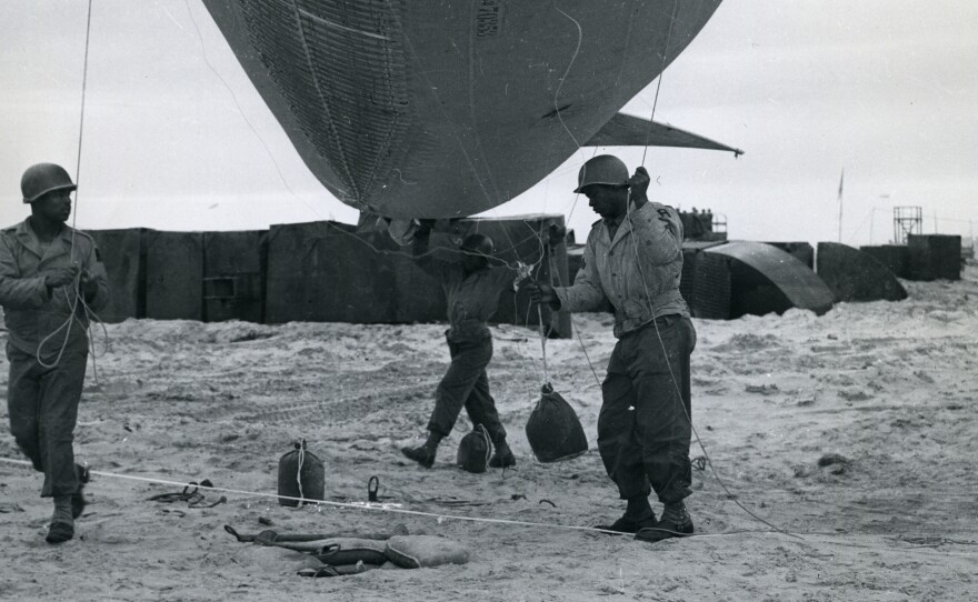 Corporal A. Johnson, from Houston, is assisted by some of his men as they walk a balloon over to a winch, in France on July 24, 1944.