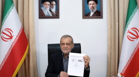 In this photo provided by the Islamic Republic News Agency (IRNA), Iranian President Masoud Pezeshkian displays a memorandum of understanding signed with U.S. President Trump aimed at ending the war and launching negotiations on a broader agreement, in Tehran, Iran, early Thursday.