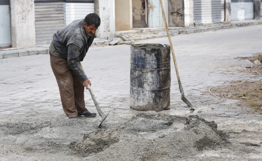 A workman with the U.N. Development Programme to rehabilitate Homs fills a pothole at the beginning of reconstruction in a city that has seen very little so far.
