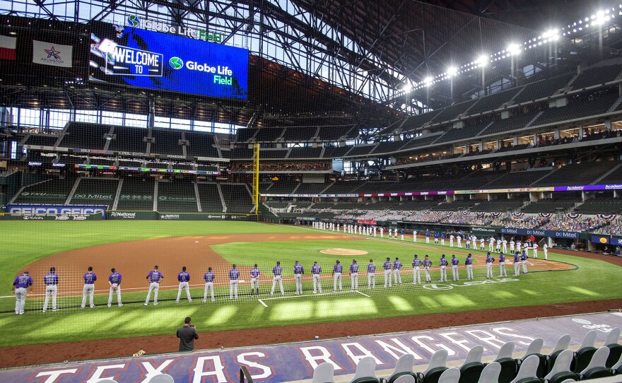 FILE - The Texas Rangers and Colorado Rockies line the foul lines of Globe Life Field before an opening day baseball game in Arlington, Texas, July 24, 2020.