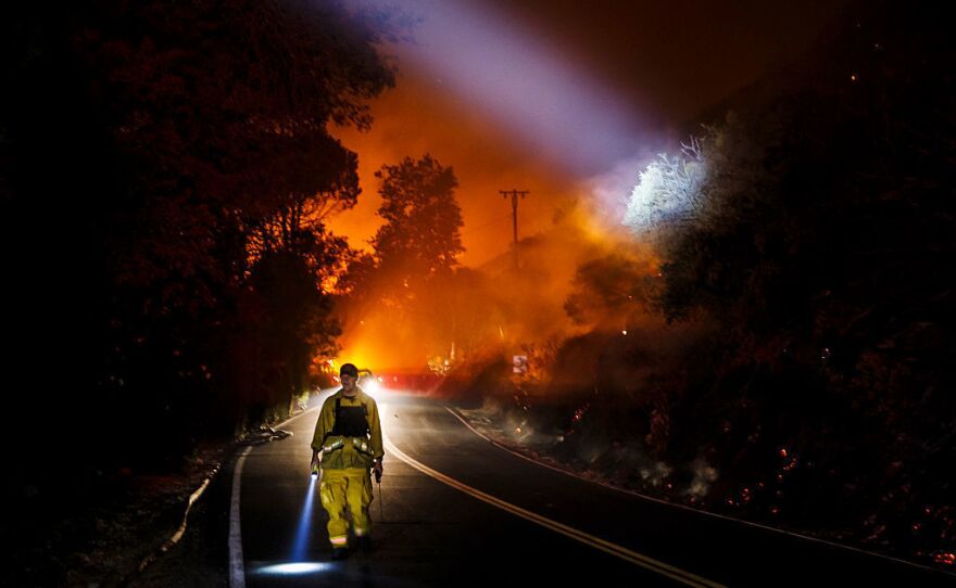 A firefighter point their beam lights around a burnt area to check for damages made by the Blue Cut fire.