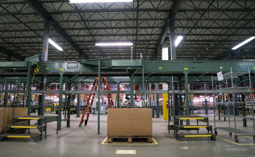 A conveyor belt, one of two types of automation at the Radial warehouse, fetches boxes from the packing station and sorts them by shipping type, depositing them directly into bins with labels like "USPS".