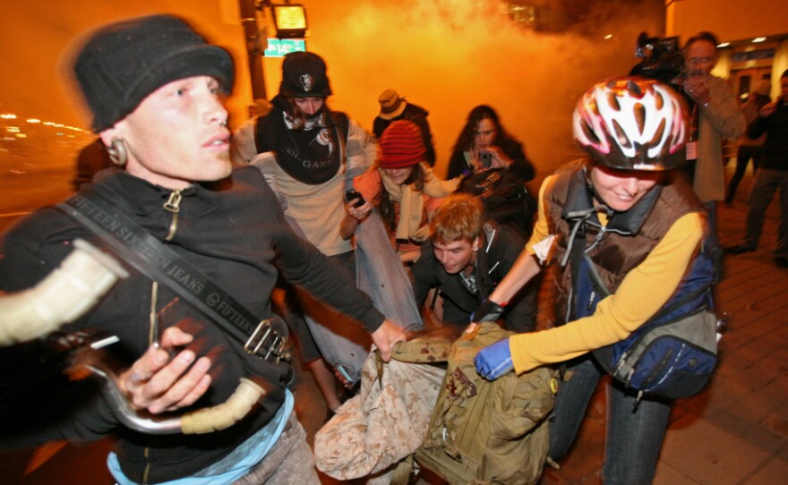 <p>Occupy Oakland protesters carry away a man who was hit by a police tear gas canister Tuesday near the Oakland City Hall.</p>