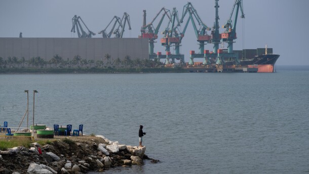 A man fishes next to shipping equipment  in Indonesia's Morowali Industrial Park in December 2025.