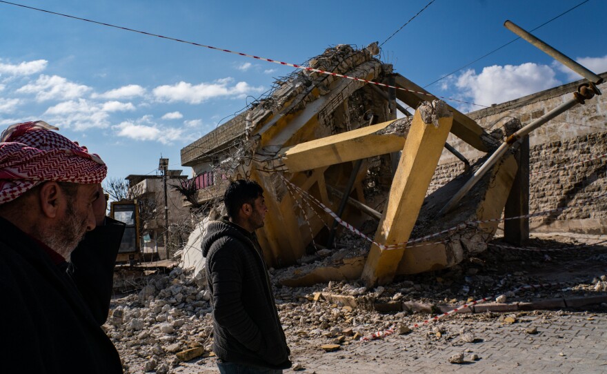 Locals walk past a damaged water tank in the Syrian town of Sawran, on Friday, days after a massive earthquake hit the region.
