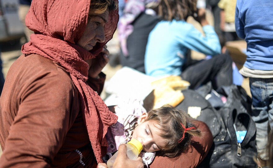 A Syrian Kurd woman gives a bottle to a child Saturday, after they crossed the border between Syria and Turkey.