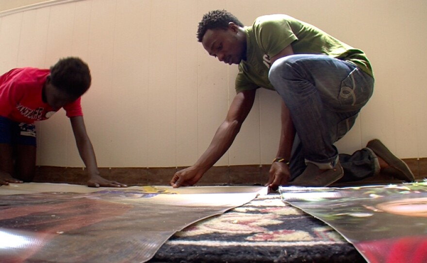 Sedrick Ntwali helps with displays meant to educate the community about the refugee experience.