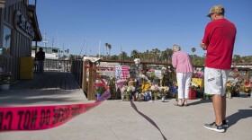People gather around a memorial for the victims of the Conception dive boat fire as authorities search the Truth Aquatics' offices, the California company that owned the scuba diving boat that caught fire and killed dozens of people last week, on the Santa Barbara Harbor in Santa Barbara, Calif., Sunday, Sept. 8, 2019. 