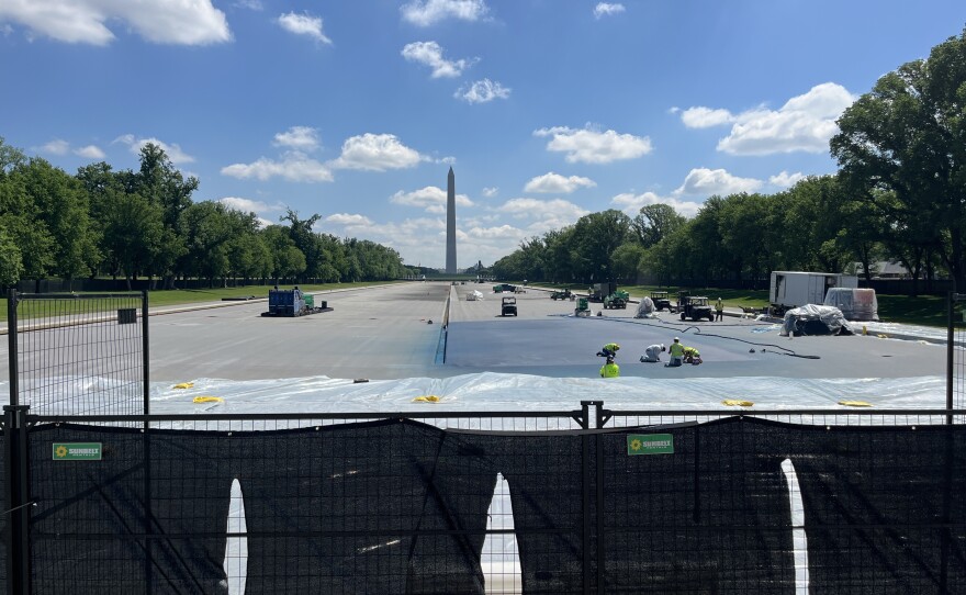 Workers paint a corner of the reflecting pool blue on Monday morning.