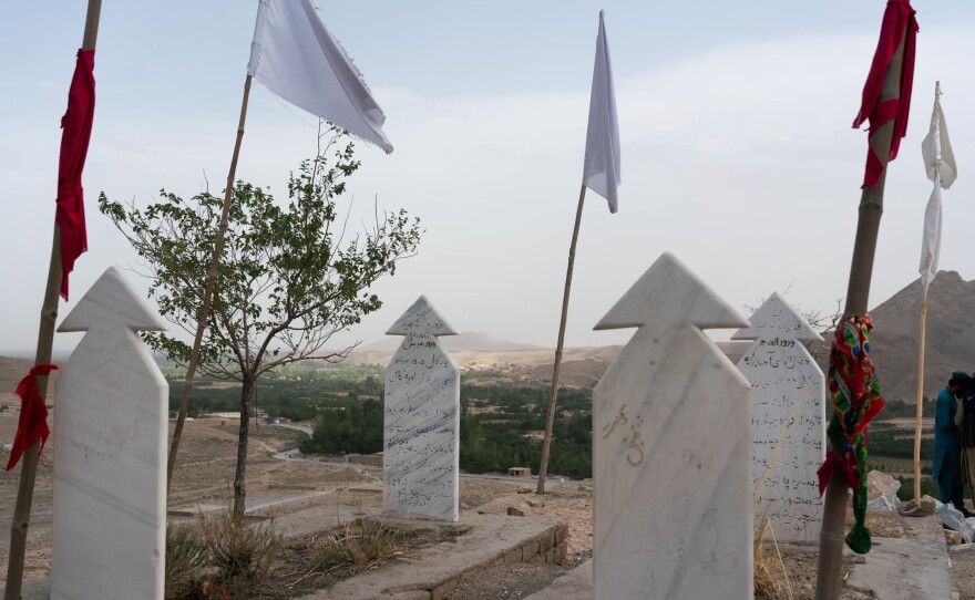 White flags stand over a shrine to the dead. Graves mark places for Mohammadi's brother and the late Taliban leader, Fazel Rabie.