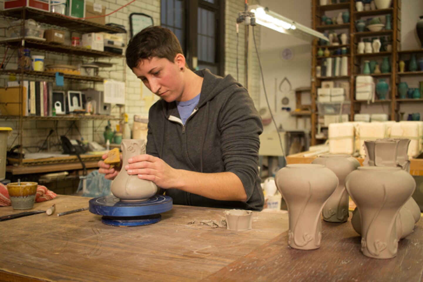 Jamie Hickey sponges and cleans up the slip cast Snowdrop Vase (Pewabic).