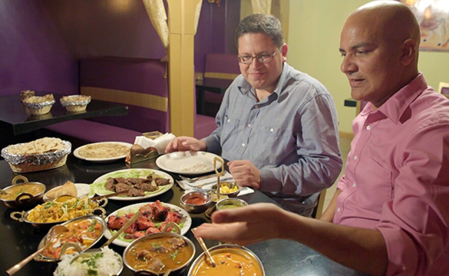 Ramesh Kumar (right) spreads out Punjabi food for host Jorge Meraz (left) at the first Indian restaurant in Tijuana, Mexico.