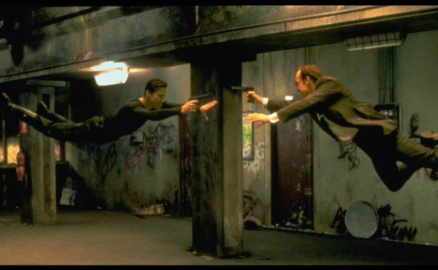Keanu Reeves and Hugo Weaving face each other in a scene from The Matrix.