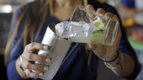 Bartender Rafaella Demelo adds sugar, 1.5 ounces of Leblon, and half a lime over ice in a shaker while preparing a caipirinha, Brazil's trademark cocktail.