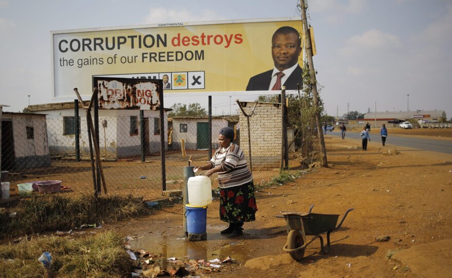 A women fills up water buckets in front of an election billboard near Johannesburg, South Africa, on Tuesday. Opposition political parties, like the one featured here, say that corruption is a major problem in the ruling African National Congress.