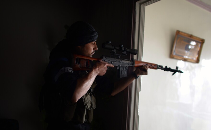 A Syrian rebel aims his sniper at Syrian government forces in the Sheikh Maqsud district of Aleppo, in April.
