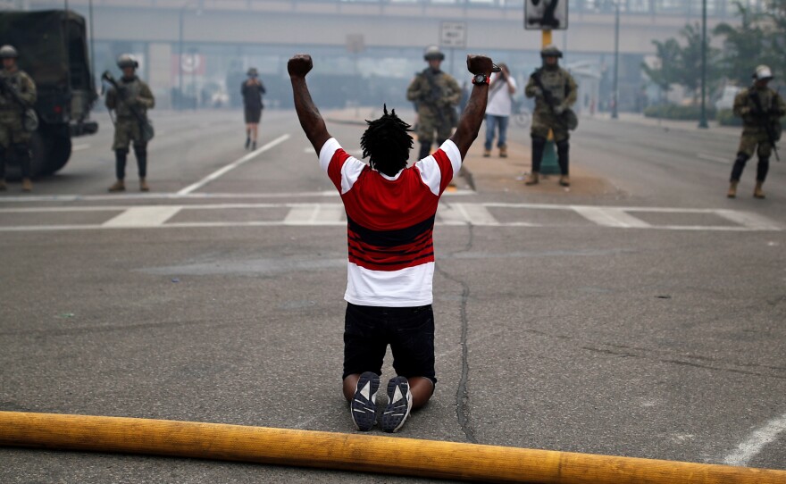 A man kneels as he confronts National Guard members guarding the area in the aftermath of a protest in Minneapolis.
