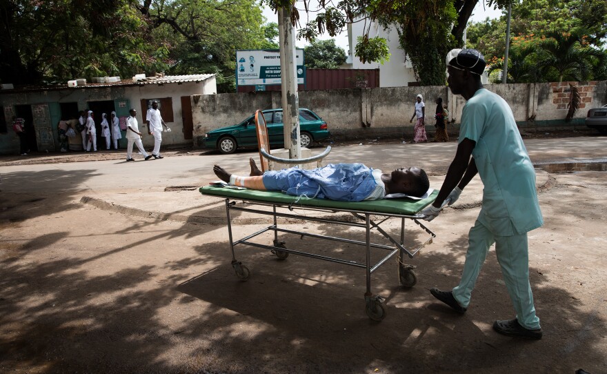 After surgery on his busted knee, 14-year-old David is wheeled across a potholed road to the pediatric ward of the Edward Francis Small Teaching Hospital.
