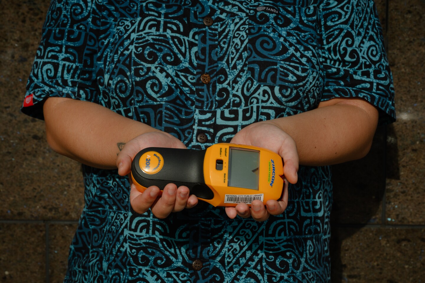 Noel Nguyen, a library assistant, holds a stud finder outside the National City Public Library in National City, California on October 13, 2025. Nguyen helps with u-Tool-ize, the library's new tool lending program.