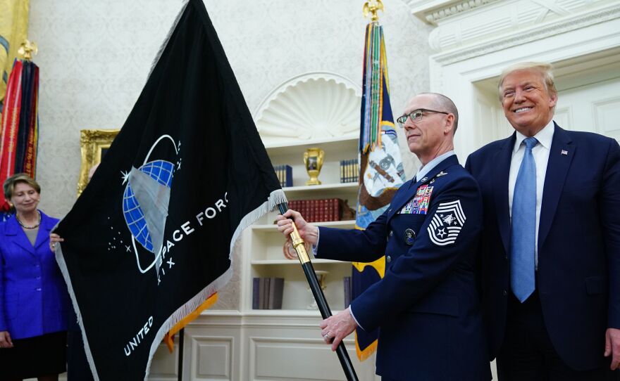 President Trump presedisplays the U.S. Space Force flag in the Oval Office last May. The new command plans to move its headquarters from a temporary location in Colorado to Alabama in 2023.