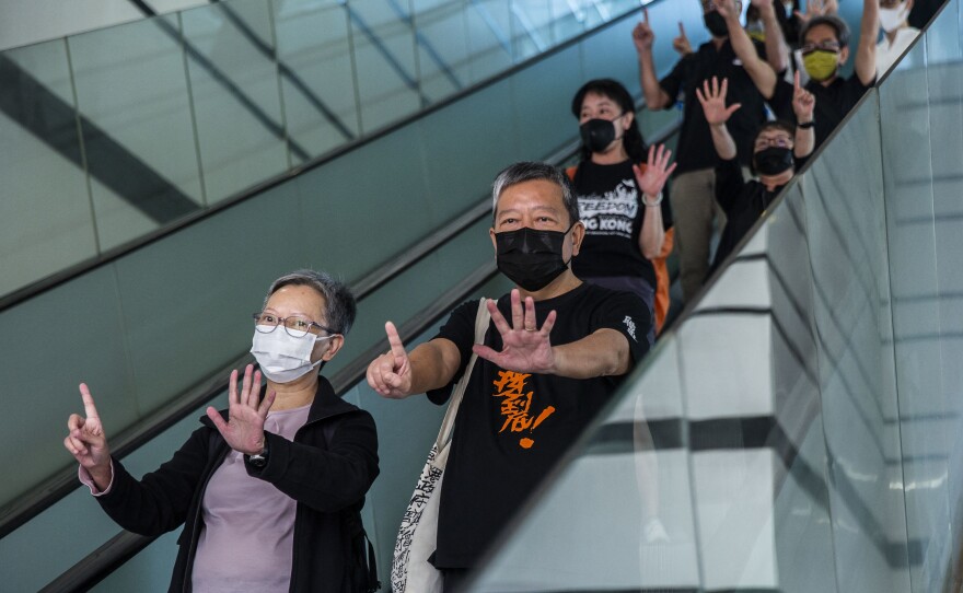 Former lawmaker Cyd Ho (left) and pro-democracy activist Lee Cheuk-yan (center) gesture a protest slogan, "Five demands, not one less," as they leave West Kowloon court in Hong Kong on Thursday after being found guilty of organizing an unauthorized assembly.