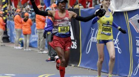 Meb Keflezighi, left, of San Diego, and Hilary Dionne, of Boston, finish the Boston Marathon, April 20, 2015 in Boston. 