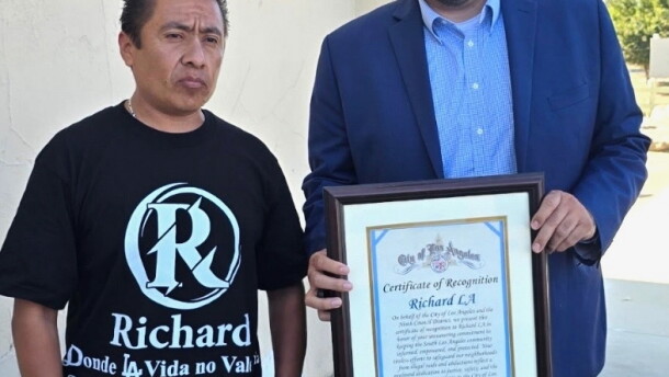 Carlitos Ricardo Parias (left) receives a certificate of recognition from Jose Ugarte, chief of staff for Los Angeles City Council member Curren Price, in Los Angeles in August 2025.