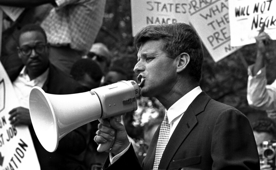 Attorney General Robert F. "Bobby" Kennedy uses a bullhorn to address a crowd of demonstrators, June 14, 1963, at the Justice Department. Four months earlier he had walked 50 miles in one day to prove to his brother John that he could do it. His march helped make extreme walking and hiking popular activities.