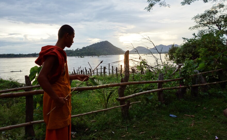 A Buddhist monk walks at sunset on Don Sadam island.