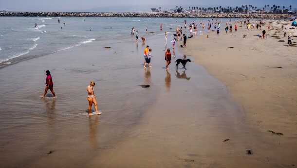People and their pets walk along the sand at Dog Beach in Ocean Beach, Sept. 6, 2021.