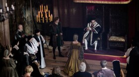 A crowd gathers around the throne as Anne Boleyn (Claire Cooper) gift King Henry VIII (Scott Arthur) a golden boat.