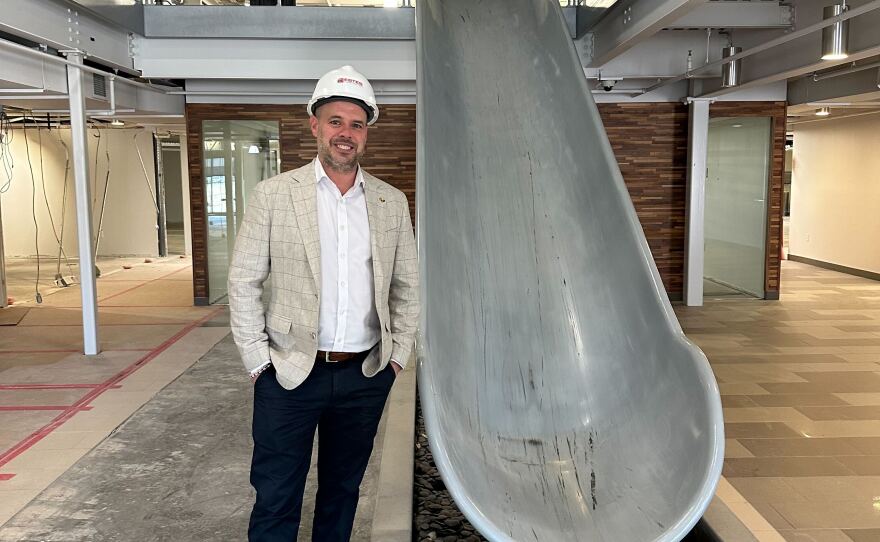 Cedar Rapids Prep's former principal, Justin Blietz, poses next to the cafeteria slide at the charter school's future home in February.