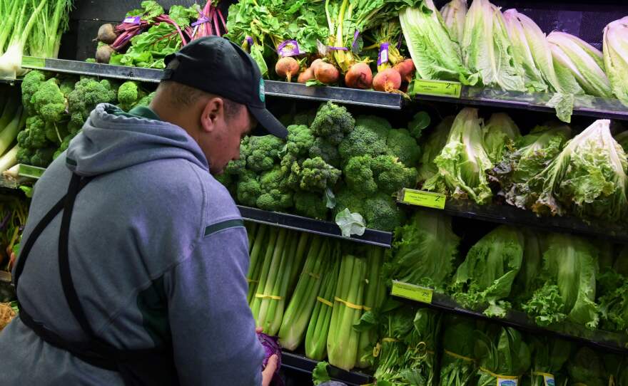 A worker stocks shelves of produce at a supermarket in Washington, D.C., in 2018. Grocery stores provide food access and jobs in a community.