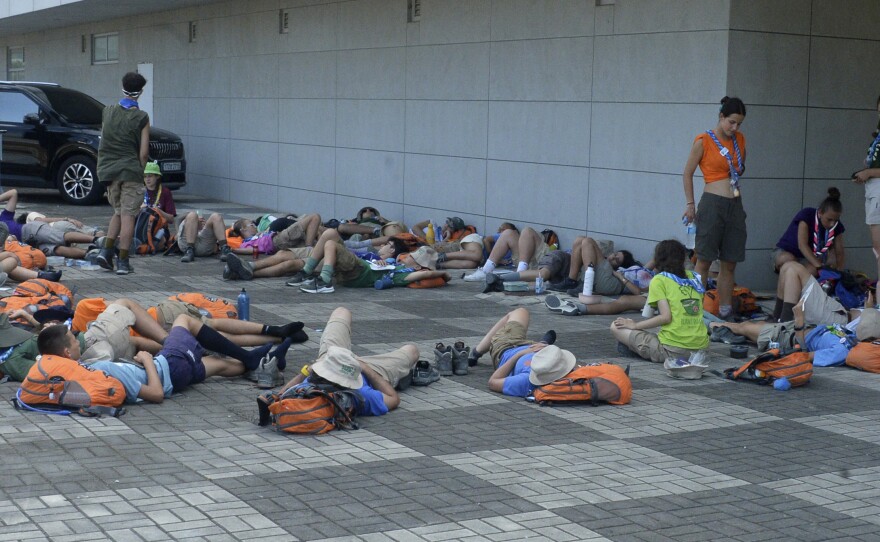 Attendees of the World Scout Jamboree lie down to rest at a scout camping site in Buan, South Korea, on Friday.