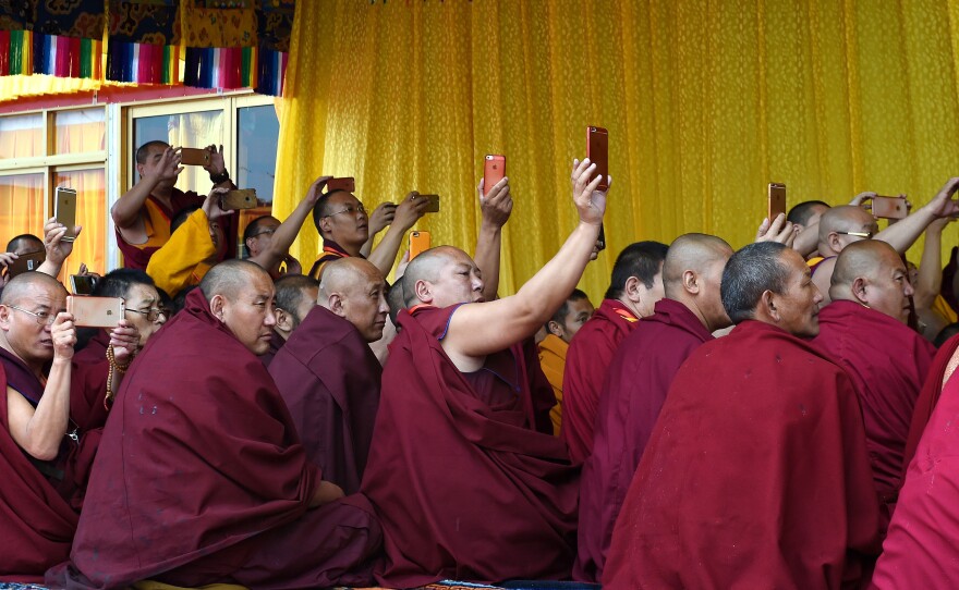 In a photo provided by China's Xinhua News Agency, Tibetan monks take smartphone pictures during the Kalachakra ritual in Tibet.