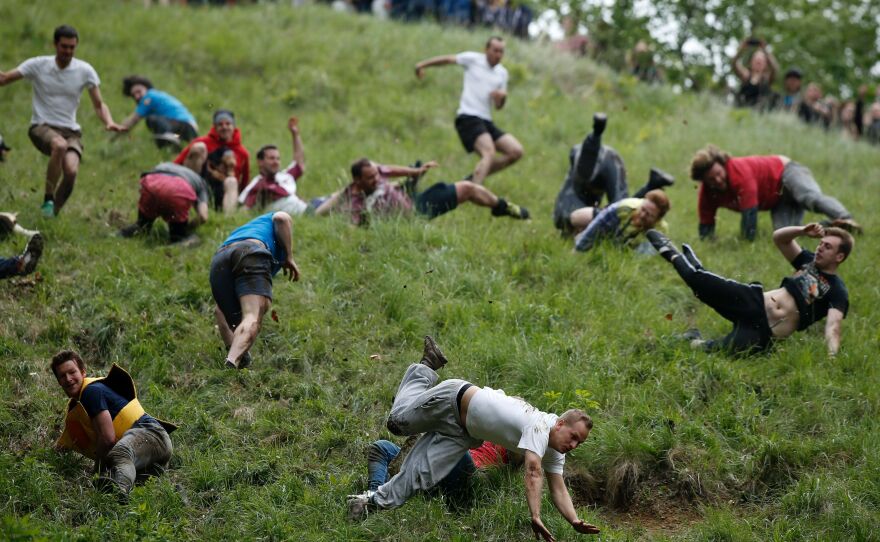 Competitors tumble down Coopers Hill in pursuit of a round Double Gloucester cheese during the 2016 cheese rolling competition near the village of Brockworth, Gloucester.