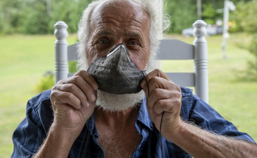 Danny Johnson, a retired coal miner with complicated black lung, holds a protective mask that used to be white, but turned black and crusted with dust during one working shift in a mine.
