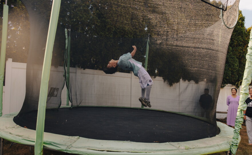 Aaron Tamang, 9, jumps on his trampoline while his sister, Naishi Tamang, 13, and his mom, Nir Tamang, look on in Harrisburg, Pa., on Sept. 14, 2025. Aaron is a player in ARU's Soccer for Success program.