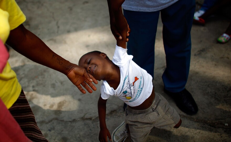 A boy falls to the ground and is helped up by the caretakers at the Maison des Enfants de Dieu Orphanage in Port-au-Prince.