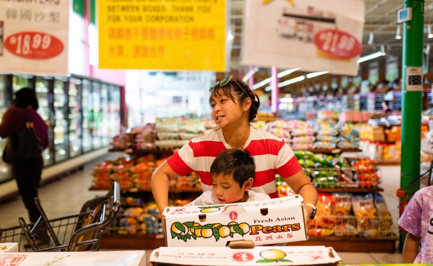 Thu helps Hayle pick up a box of Asian pears at a grocery store in Eden Center in Falls Church, Va., on Oct. 12, 2019.