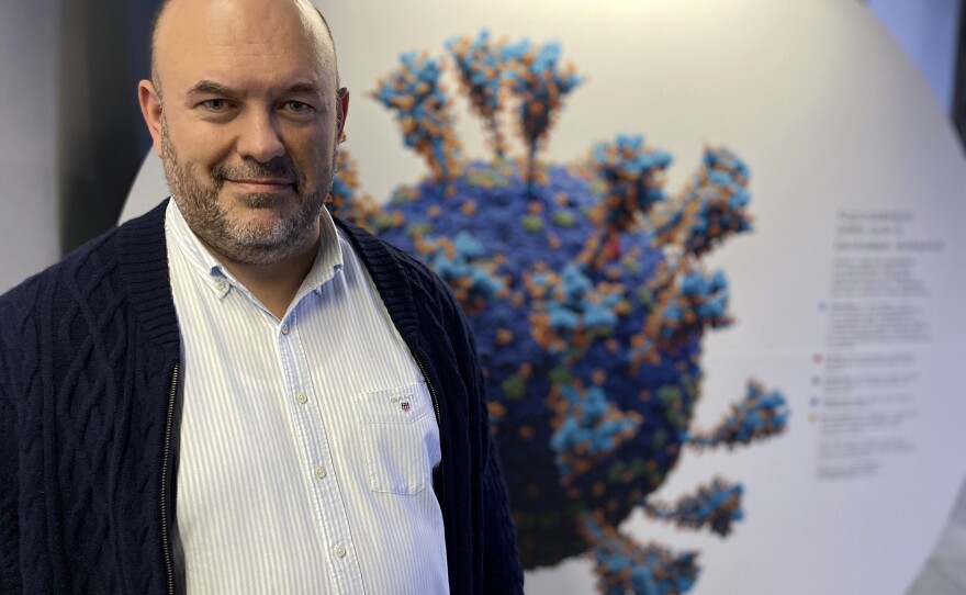 Sergei Rikov, curator of the exhibit "Life with Viruses" in Moscow, poses before a model of the coronavirus. Rikov argues the exhibit can play a role in educating Russians about the coronavirus — and the need to vaccinate.