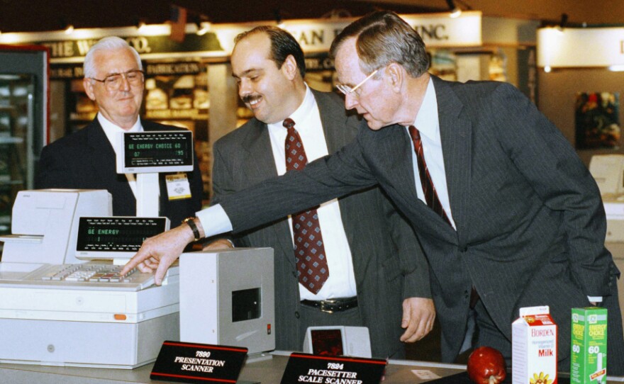President George H.W. Bush (right) pushes the keys on a new high-technology cash register under the watchful eyes of Leo Hardy (left) and Bob Graham during a visit to the National Grocers Association trade show on Feb. 4, 1992, in Orlando, Fla. <a href="http://www.nytimes.com/1992/02/05/us/bush-encounters-the-supermarket-amazed.html">Media accounts</a> portrayed the president as being "amazed."