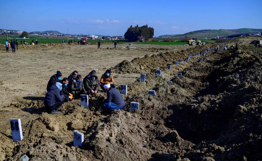 People mourn their lost relatives at a mass grave in Hatay, Turkey, four days after the deadly 7.8 magnitude earthquake has killed thousands of people.