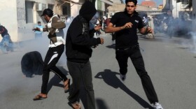 Bahraini protestors run for cover after police fired tear gas canisters to disperse them in the village of Diraz, northwest of Bahrain.