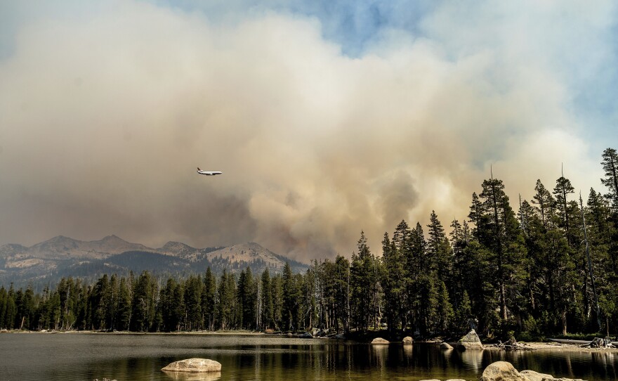 A tanker flies over Wrights Lake while battling the Caldor Fire in Eldorado National Forest, Calif., on Wednesday, Sept. 1, 2021.