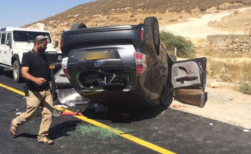 An Israeli security officer next to an overturned vehicle belonging to a family of Jewish settlers ambushed near Hebron, in the West Bank, on July 1. Two Palestinians aided the wounded Israelis. One of the Palestinians has since lost his job and been targeted for abuse by fellow Palestinians.