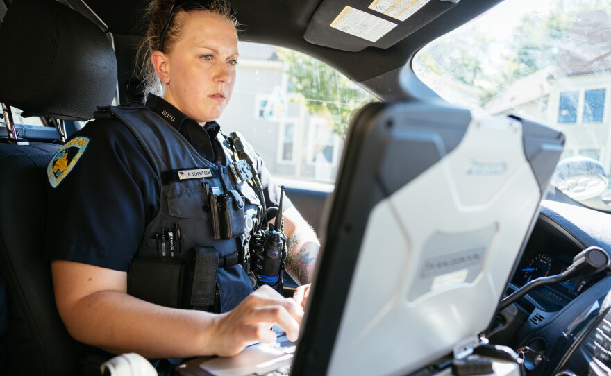 Officer Nicole Schmitgen works on her computer during her patrol in Madison, Wis.