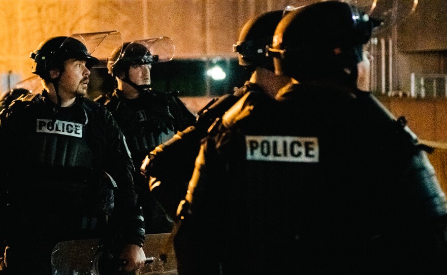 Police officers stand guard inside of a fenced area that surrounds several government buildings in Kenosha, Wis., on Thursday.